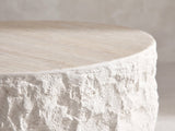 Close-up of the Piombino Faux Travertine Fiberglass Drum Coffee Table: the rock-face side rising to the travertine-look top