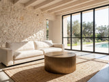 Pitigliano Brass-Finish Fluted Drum Coffee Table on a jute rug in front of a linen sofa in a poolside villa