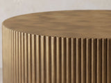 Close-up of the Pitigliano Brass-Finish Fluted Drum Coffee Table: the narrow brass-finish reeds meeting the scalloped edge of the top