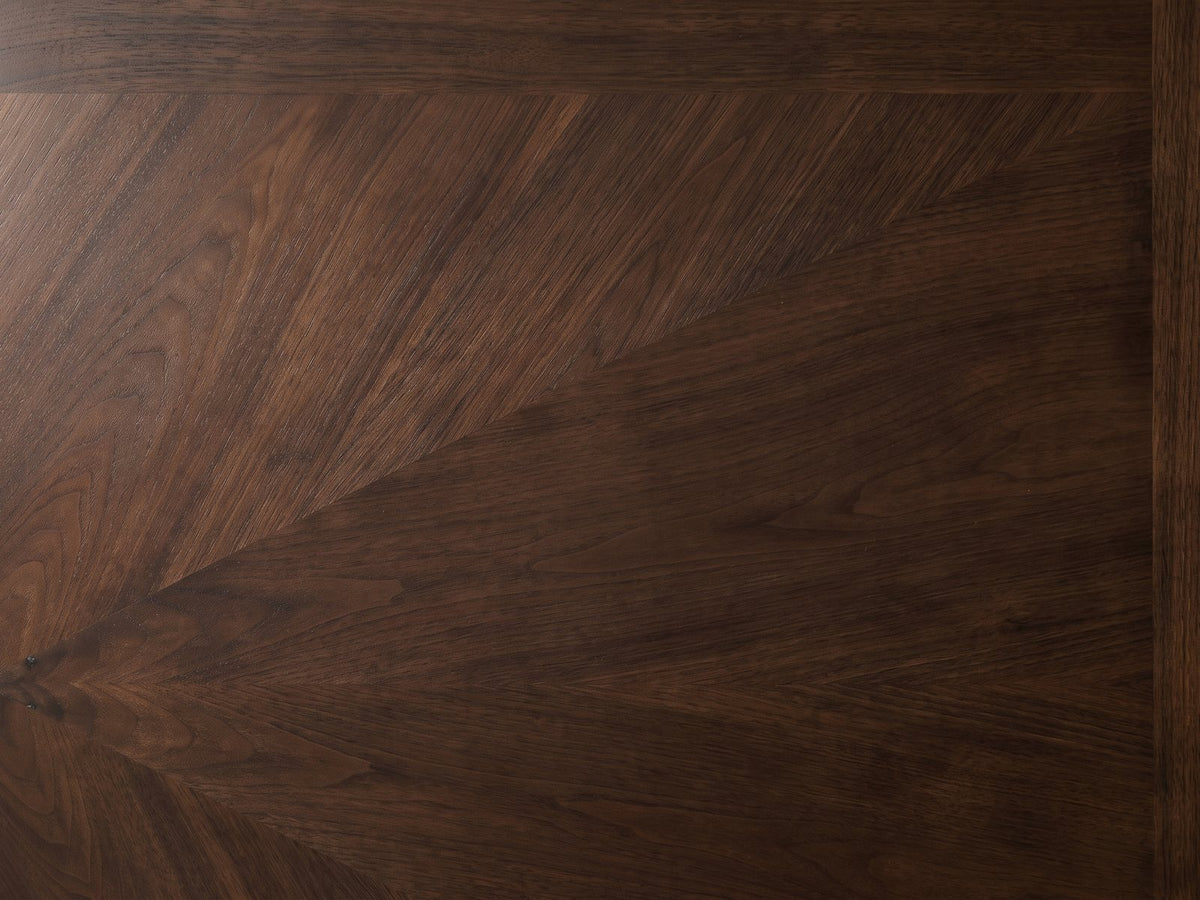 Close-up of the Pizzo 76-Inch Walnut Veneer Extending Trestle Dining Set with Bench and 4 Chairs: the fan-matched walnut veneer of the top inside its cross-banded border