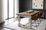 Policoro fir plank dining table with carved antique-white urn legs in a Chicago dining room with a charcoal panelled wall, a white wool rug and a walnut herringbone floor