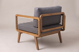 The Polizzi lounge armchair from behind: the rounded back frame with eight rope strands, the grey back cushion and one rope-strung arm