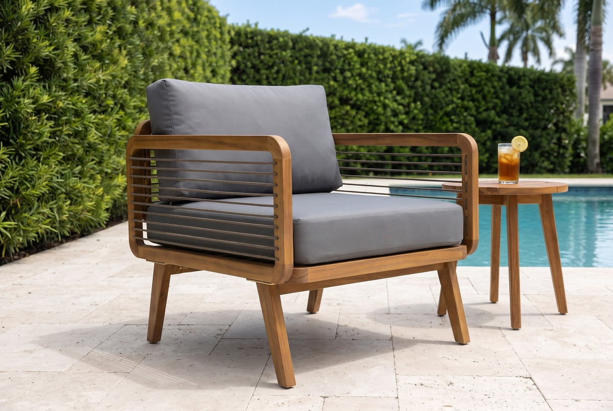 Polizzi acacia lounge armchair on ivory travertine beside a pool in Naples, Florida, a clipped green hedge and royal palms behind (side table and glass not included)