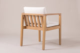 A Pollina dining armchair seen from behind: the reclined back with five vertical acacia slats, the ivory back cushion above it