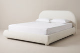 The Pollutri bed in cream boucle with a white mattress and pillows (not included), three-quarter view on a light studio backdrop
