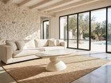Ponza Milk White Fiberglass Pebble Coffee Table on a jute rug in front of a linen sofa in a poolside villa