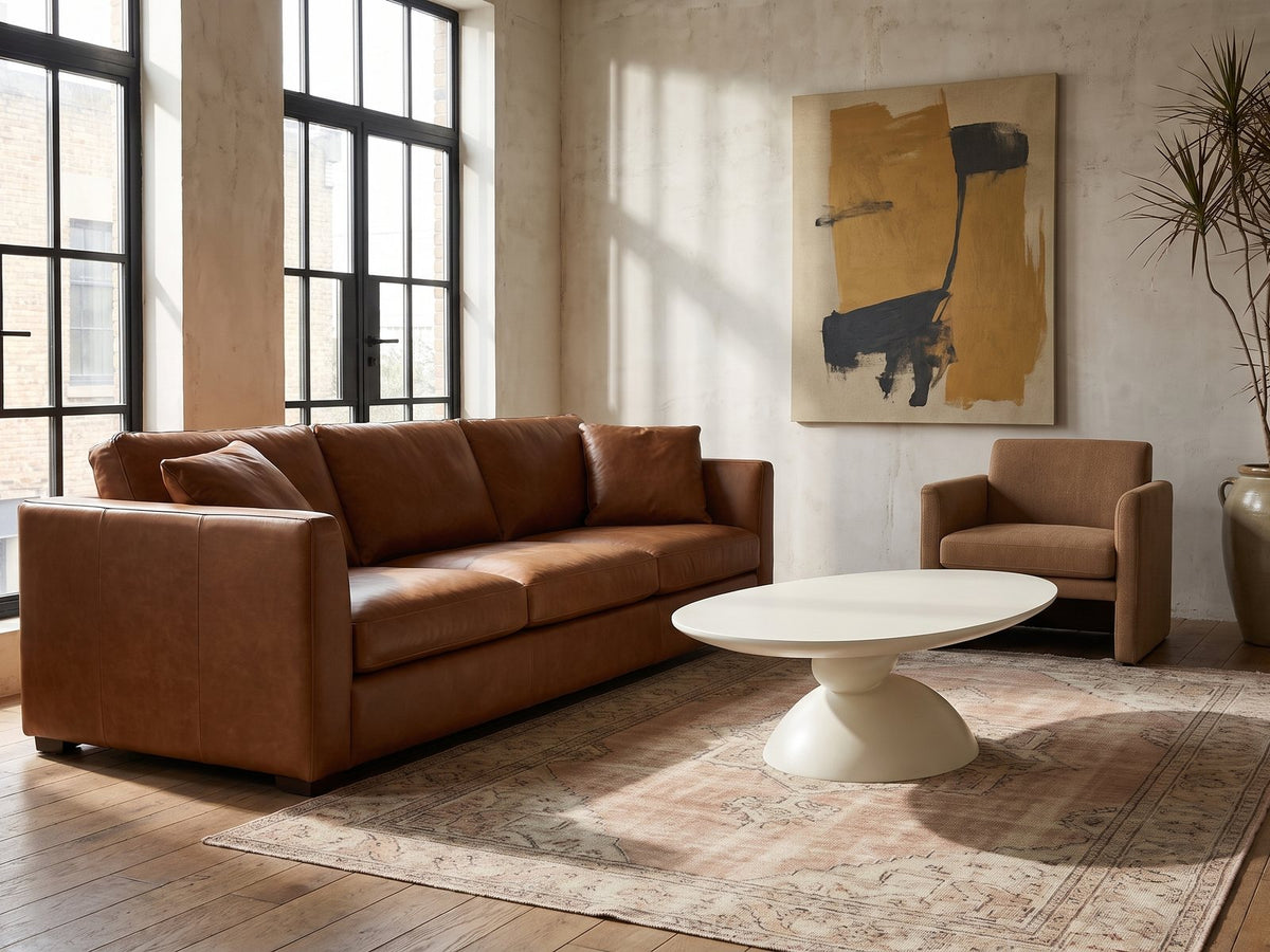 Ponza Milk White Fiberglass Pebble Coffee Table on a vintage rug in front of a leather sofa in an industrial loft