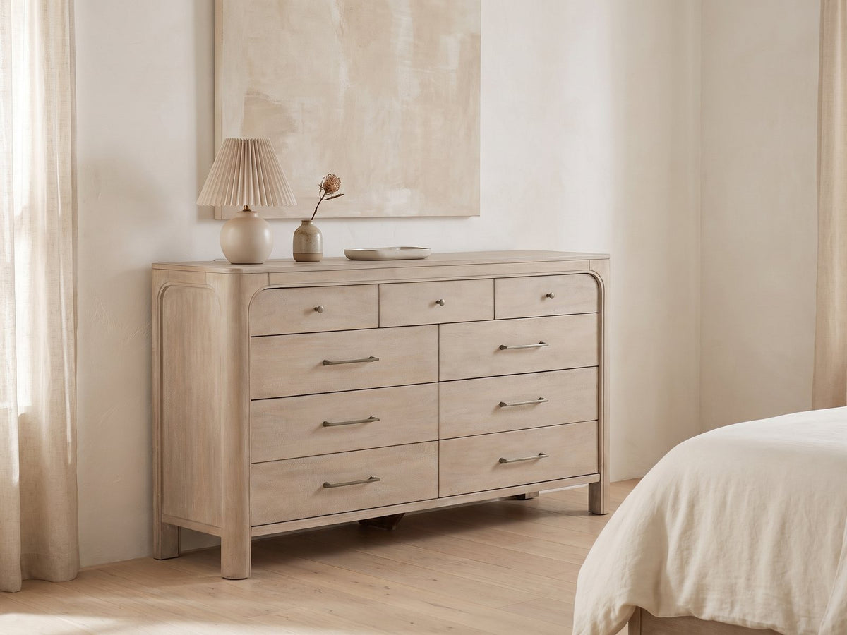 Portogruaro 70-Inch Weathered Mango 9-Drawer Dresser against a plaster wall under an abstract canvas in a bright bedroom