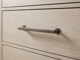 Close-up of the Portogruaro 70-Inch Weathered Mango 9-Drawer Dresser: the antique brass bar pull on a weathered mango drawer