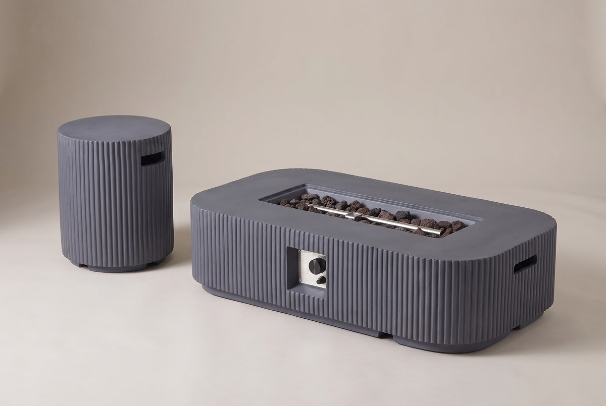 The Portopalo fire pit and its round fluted companion piece in dark gray concrete, three-quarter view on a light studio backdrop