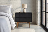 Posada black oak nightstand against a white-painted brick wall in a Chicago loft bedroom with a polished concrete floor