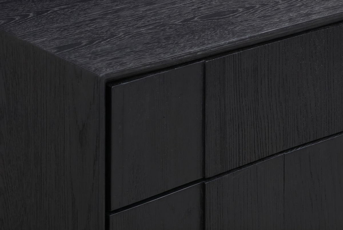 The upper corner of the Posada nightstand: the brushed black oak top and the vertical oak blocks of the drawer fronts