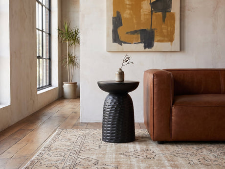 Presicce Black Mango Scalloped Pedestal Side Table beside a leather sofa in an industrial loft