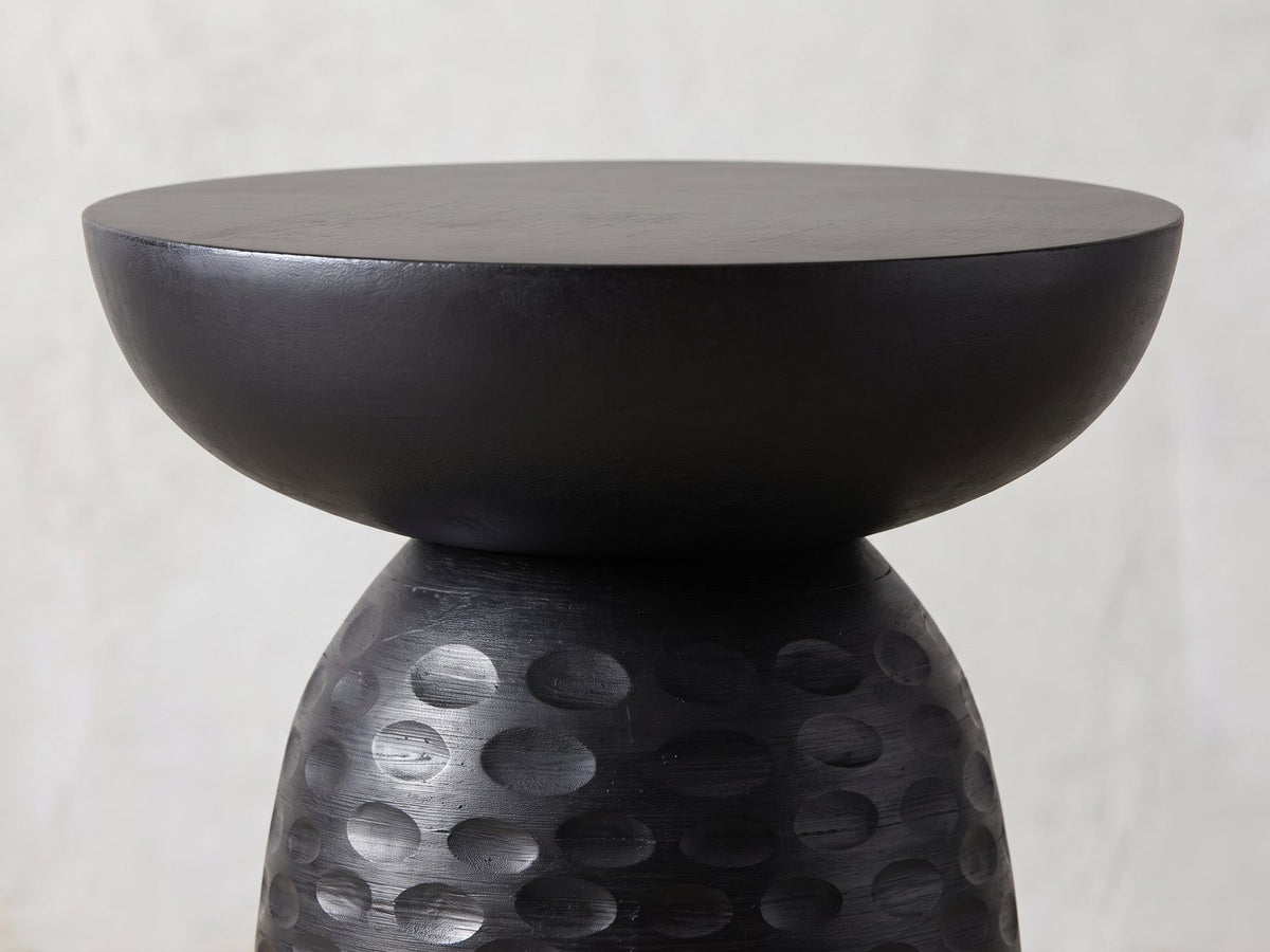 Close-up of the Presicce Black Mango Scalloped Pedestal Side Table: the smooth bowl-shaped top resting on the carved bell base