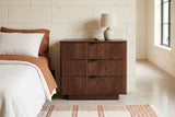 Pula reeded walnut nightstand against a pale limestone wall in an Austin Hill Country bedroom with a polished concrete floor