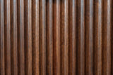 Close-up of the reeded walnut-brown solid wood on the Pula nightstand: narrow vertical reeds with lighter and darker streaks