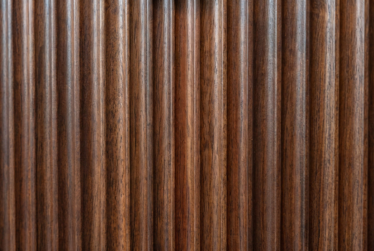 Close-up of the reeded walnut-brown solid wood on the Pula nightstand: narrow vertical reeds with lighter and darker streaks