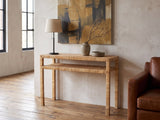 Putignano Wrapped Rattan Two-Tier Console Table against a plaster wall in an industrial loft