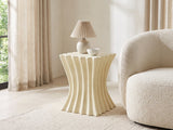 Racale Cream Fiberglass Pleated Side Table with a lamp and a ceramic bowl beside a cream boucle armchair in a bright plaster room