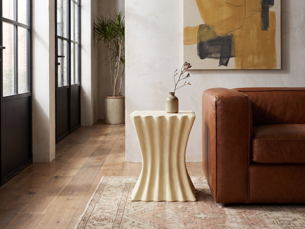 Racale Cream Fiberglass Pleated Side Table beside a leather sofa in an industrial loft