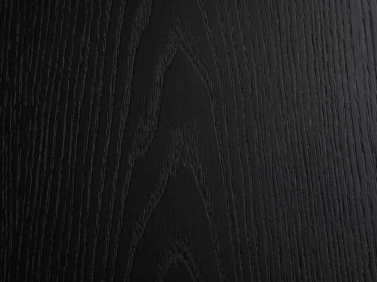 Close-up of the Radda Black Carved Wood Drum Coffee Table: the open-pore black ash grain of the top