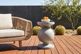 Raffadali concrete sphere pedestal side table with a bowl of oranges beside a rope lounge chair on an ipe deck in Tucson, Arizona, a charcoal board-formed concrete wall, barrel cacti and a palo verde tree (chair and decor not included)
