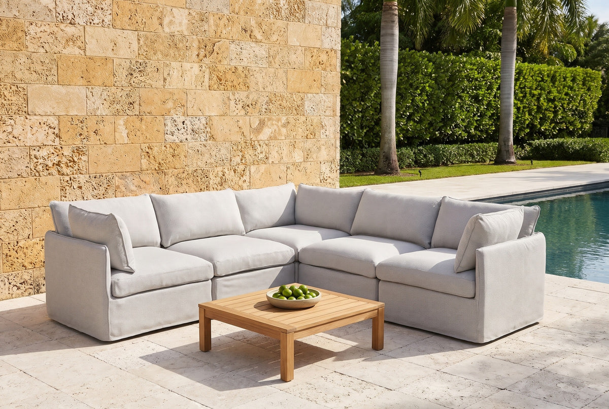 Randazzo light grey L-shaped sectional on a keystone pool terrace at a Coral Gables, Florida house, with a coral-rock wall and royal palms (coffee table not included)