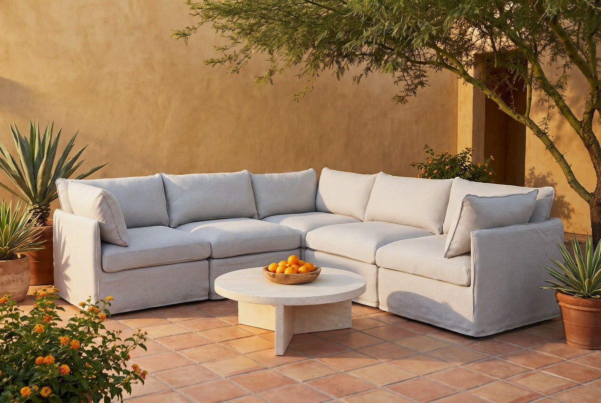 Randazzo light grey L-shaped outdoor sectional in a San Antonio, Texas courtyard at golden hour, an ochre limewash wall, Saltillo tiles and a mesquite tree (coffee table not included)