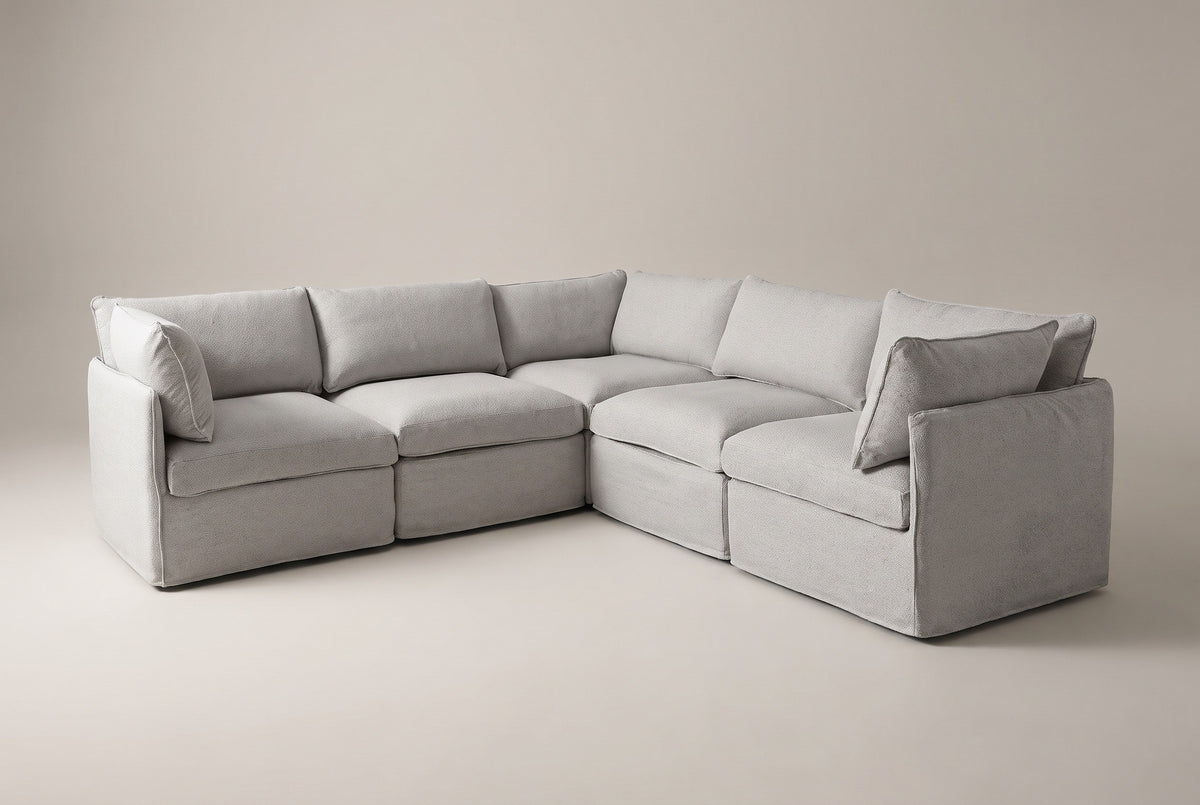 The Randazzo five-seat L-shaped sectional in light grey slipcovers, three-quarter view on a light studio backdrop