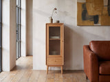 Recco Solid Oak Reeded Glass Storage Cabinet against a plaster wall in an industrial loft