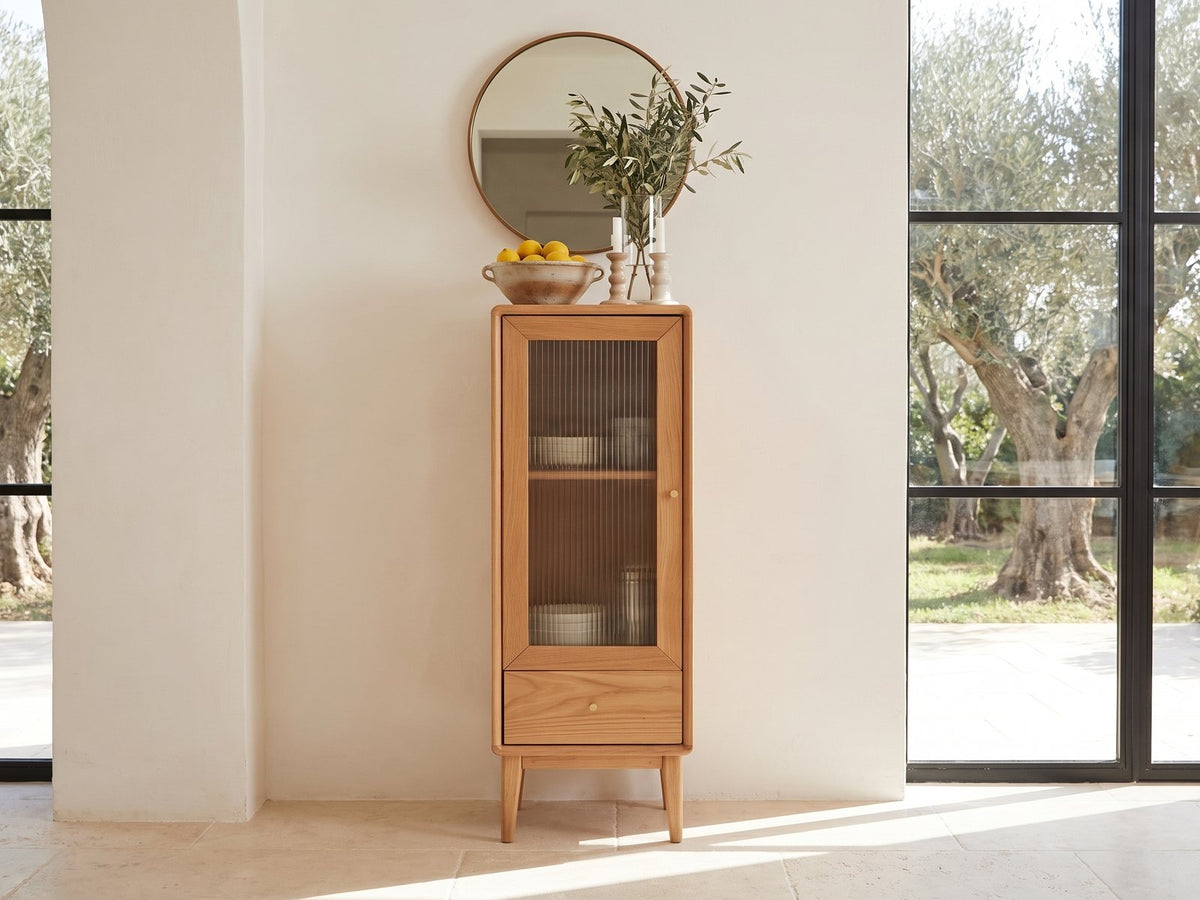Recco Solid Oak Reeded Glass Storage Cabinet against a plaster wall in a sunlit Mediterranean villa