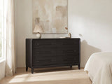 Recoaro 54-Inch Peppercorn Black 6-Drawer Dresser against a plaster wall under an abstract canvas in a bright bedroom