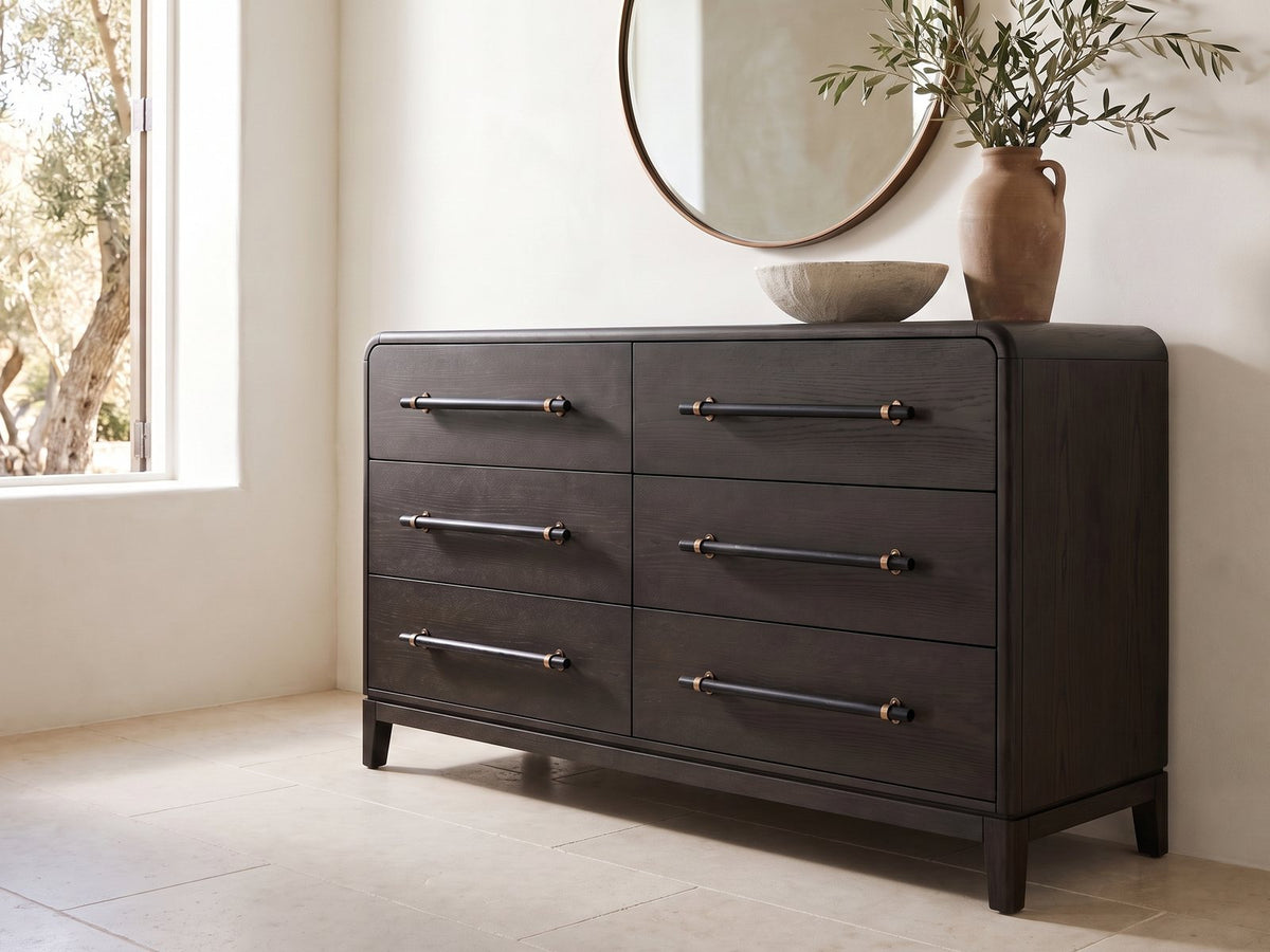 Recoaro 54-Inch Peppercorn Black 6-Drawer Dresser under a round bronze mirror in a villa bedroom
