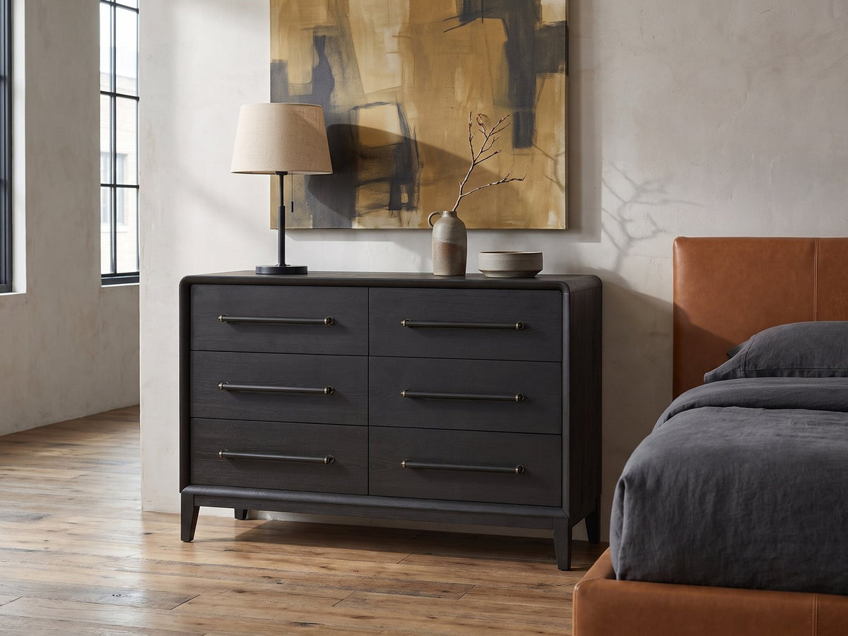 Recoaro 54-Inch Peppercorn Black 6-Drawer Dresser against a plaster wall in an industrial loft bedroom
