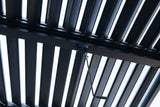 Looking up at the Regalbuto roof: black aluminum louvers tilted open under the sky, a cross beam, the gearbox and the crank hook