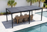 Regalbuto black louvered pergola over a teak dining table for eight on pale pavers beside a pool in Tampa, a white board-and-batten wall and palms behind (furniture not included)