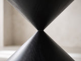 Close-up of the Rende 59-Inch Round Black Oak Hourglass Dining Set with 6 Chairs: the narrow waist where the two black oak cones of the hourglass pedestal meet