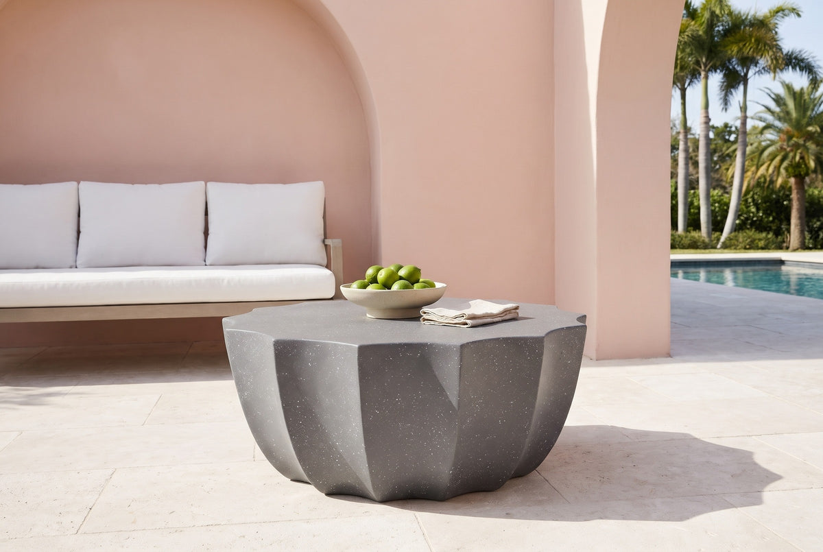Ribera speckled gray coffee table on cream limestone in a Coral Gables pool loggia, a blush-pink stucco wall with an arch and a white outdoor sofa behind (sofa, bowl and napkins not included)