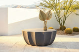 Ribera speckled gray coffee table on pale travertine in a Palm Desert courtyard at golden hour, a white stucco wall, a palo verde tree, barrel cacti and mountains behind (vase not included)