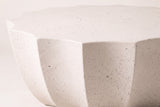 Close-up of the Ribera table in speckled white: dark flecks in the matte MgO cement at the points of the scalloped top and the concave flutes below