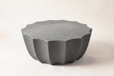 The Ribera outdoor coffee table in speckled gray MgO cement: a 14-point scalloped round top over a fluted bowl-shaped body, on a light studio backdrop