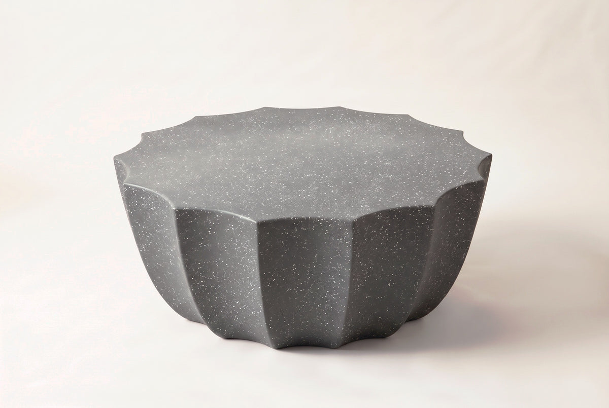 The Ribera outdoor coffee table in speckled gray MgO cement: a 14-point scalloped round top over a fluted bowl-shaped body, on a light studio backdrop