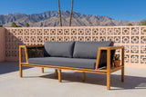 Riposto acacia daybed sofa on a Palm Springs patio in front of a peach breeze-block wall, palms and the San Jacinto mountains behind (plant not included)