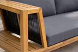 Close-up of a Riposto arm: black woven rope strands, the teak-finish acacia frame and slatted armrest, beside the grey seat cushion