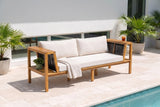 Riposto acacia daybed sofa with cream cushions on a travertine pool terrace at a modern house in Sarasota, white stucco wall and potted palms behind (throw and plant not included)