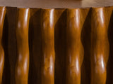 Close-up of the Rivoli 30-Inch Round Carved Wood Drum Coffee Table: carved wavy wood ribs under the edge of the sunburst top