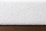 Close-up of the Roccascalegna bed where the white boucle rail meets the walnut-tone wood plinth