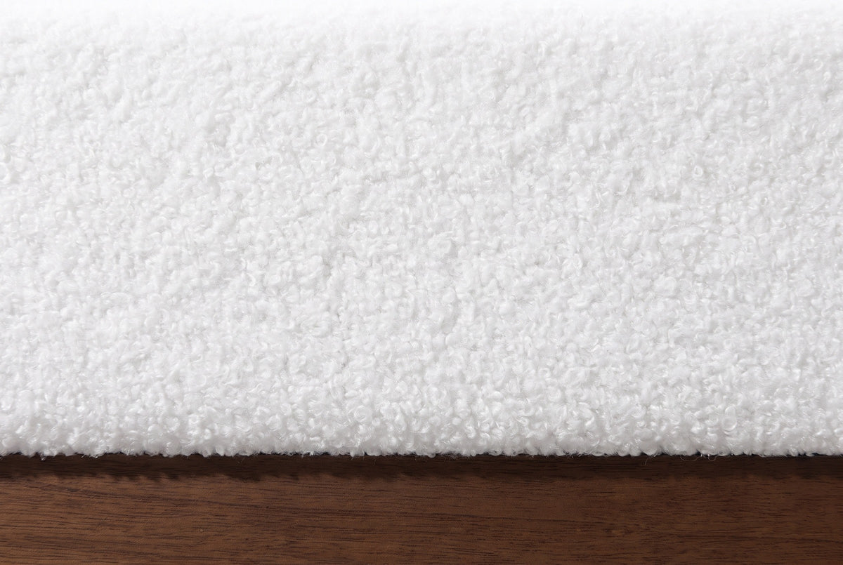 Close-up of the Roccascalegna bed where the white boucle rail meets the walnut-tone wood plinth