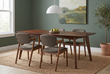 Rossano walnut-veneer dining table with four chairs against a deep sage-green plaster wall in a Portland dining room with a jute rug