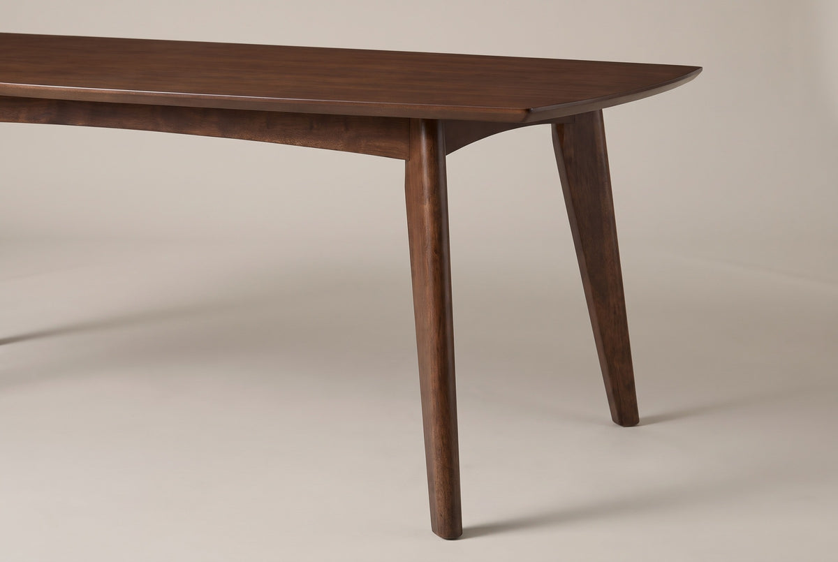 The end of the Rossano table: the thin bevelled top, the shallow arched rail and a round tapered walnut-finished leg splaying outward to the floor